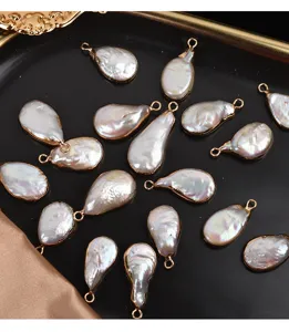 Primer plano de colgantes de perlas barrocas en gota con borde dorado para manualidades.