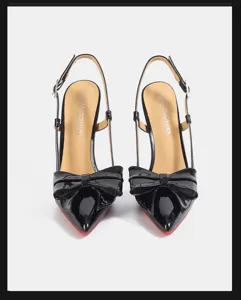 Elegant black patent leather pointed toe slingback high heels with bow and red sole.