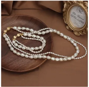 Conjunto de collar y pulsera de perlas barrocas de doble capa con elegante cierre lazo dorado.