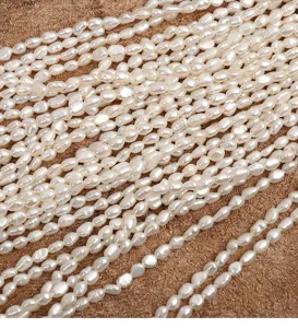 Detailed close-up of natural freshwater baroque pearls strung on threads, white shiny beads.