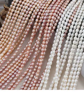 Primo piano di fili di perle d'acqua dolce di riso lisce da 4,5-5 mm, ideali per gioielli fai da te.