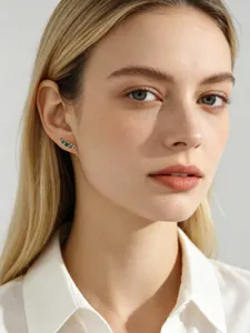 Close-up detail of S925 sterling silver stud earrings with green zircons worn by model