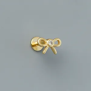 Macro view of minimalist gold bow earring with central zircon stone and flat back screw