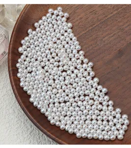 Nahaufnahme von kleinen 3-3.5mm Süßwasser Zuchtperlen auf Holzteller, DIY Perlenschmuck Detail.