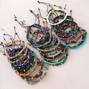 Vista dettagliata dei bracciali intrecciati regolabili in perle cilindriche di pietra.