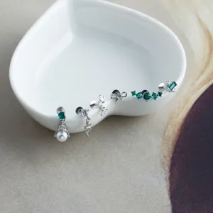 Close-up of S925 sterling silver piercing earrings with green cubic zirconia accents