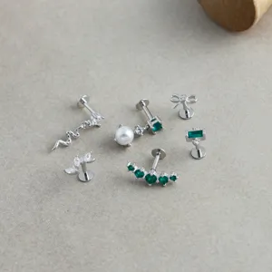 Detailed view of S925 sterling silver piercing studs with green zircon and pearl accents