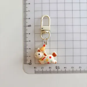 Detail shot of cute cartoon pony keychain charm with party hat and colorful polka dot pattern.