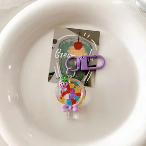 Close-up detail of a cute summer rainbow transparent lollipop keychain with purple bow and strawberry.