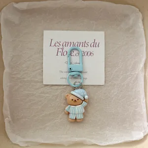 Cute cartoon sleeping bear keychain with blue striped pajamas and metal clasp bag pendant.