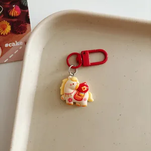 Detailed shot of a cute cartoon horse keychain with red metal clasp on a beige tray.