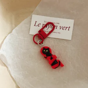 Close-up detail of the cute black cat keychain with a red clasp, charming bag accessory gift.