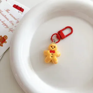 Cute gingerbread man keychain with red clasp on white plate, perfect bag charm gift.