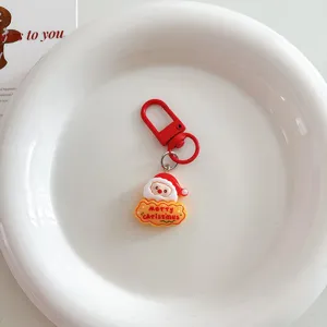 Close-up detail view of a cute cartoon Santa Claus keychain with red hook and festive design.