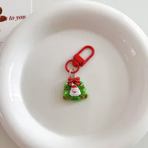 Close-up of a cute Christmas Santa Claus keychain with red clasp and wreath pendant.