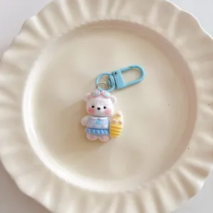 Cute surfing bear keychain detail shot, blue dress plush pendant for bags and school backpacks.