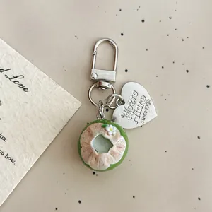 Cute green coconut food toy keychain detail, metal clasp and heart pendant, bag charm accessory.