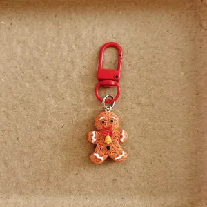 Close-up of cute gingerbread man keychain with red metal clasp, perfect holiday accessory detail.