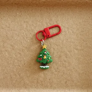 Close-up view of a cute Christmas tree keychain and bag charm featuring a red metal clasp.