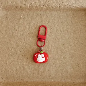 Close-up detail of the cute apple rabbit keychain and red metal clasp pendant ornament.