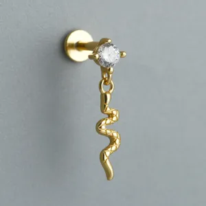 Close-up of golden snake charm labret earring with sparkling zircon and flat back