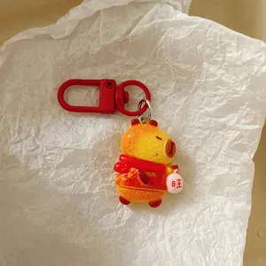 Cute red capybara keychain detail, festive pendant with scarf for backpack bag charm.