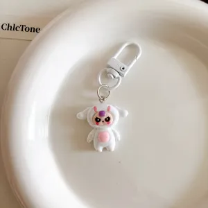 Cute cartoon monster keychain detail, white designer toy bag charm pendant accessory.