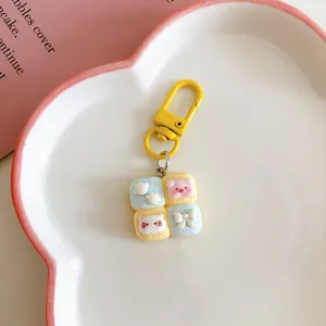 Detailed shot of cute cartoon 4-grid bread cat and pig keychain pendant, sweet bag charm.