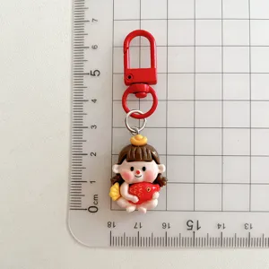 Close-up detail of cute cartoon Fuwa keychain with red hook on grid measuring board.