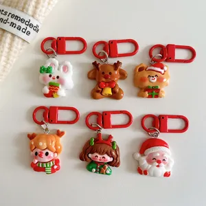 Detailaufnahme süßer Weihnachtsmann- und Rentier-Schlüsselanhänger mit roten Karabinern.