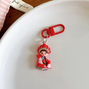 Close up of a cute Chinese opera character keychain pendant, red resin charm detail.