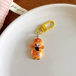 Close-up detail of a cute Chinese opera character keychain pendant in bright yellow.