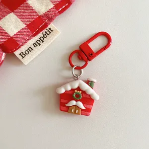 Detailed shot of cute Christmas house keychain pendant with red clasp and festive holiday design.