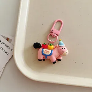 Cute pink pony keychain with party hat and fruit pendant, perfect bag charm and student gift.