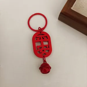 Nahaufnahme des roten Holz-Schlüsselanhängers mit chinesischen Zeichen und kleiner Glocke.