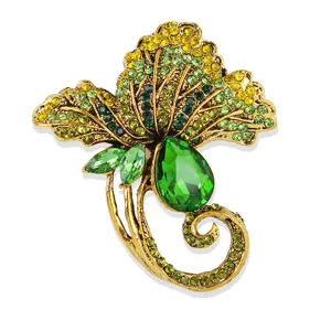 Detail van vintage goudkleurige blad broche versierd met sprankelende kristallen.