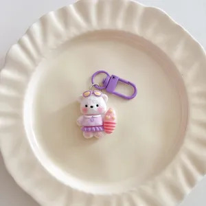 Cute surfing bear keychain detail close up, purple dress with surfboard bag charm pendant.