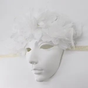 Nahaufnahme der eleganten weißen Maskenballmaske mit Federn, Spitze und feinen Perlen.