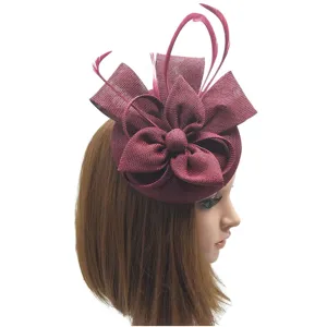 Detalle de primer plano del elegante sombrero fascinador rojo vino con plumas y lazo de malla.