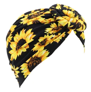 Detalle en primer plano del turbante retorcido con estampado de girasol negro en seda.