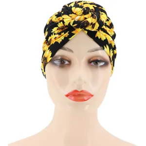 Detalle cercano del sombrero turbante estampado de girasol negro con elegante nudo en espiral.