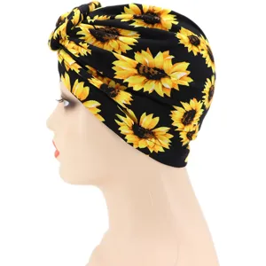 Vista detallada del turbante negro con estampado de girasol, mostrando el nudo y detalles florales.