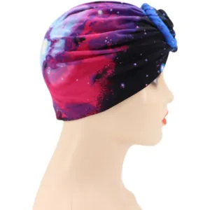 Vista detallada de un turbante de seda de leche con estampado galaxia y nudo frontal.