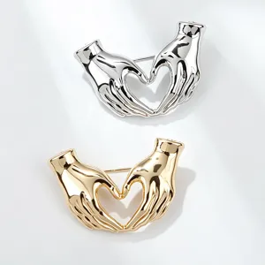 Close-up detail of stylish metal hand heart brooch, creative clothing accessory pin design.