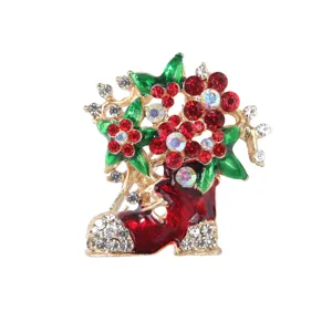 Gros plan sur une broche botte de Noël ornée de cristaux rouges et de détails dorés.
