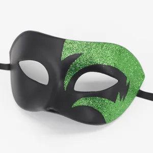 Detailopname van een zwart carnavalsmasker met opvallende groene glitterdetails.