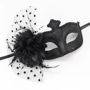 Gros plan du masque noir avec résille à pois et décoration élégante de fleurs et plumes.