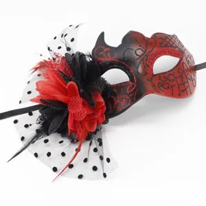 Close-up detail of a red and black masquerade mask featuring fabric flowers and a veil