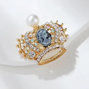 Detailed view of the vintage gold crown brooch with shimmering rhinestones and cameo portrait.