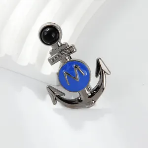 Detailed shot of a stylish naval style anchor brooch with blue enamel and letter M accent.
